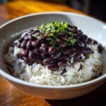 Close-up of a bowl filled with white rice topped generously with seasoned black beans and fresh cilantro, perfect beans and rice.
