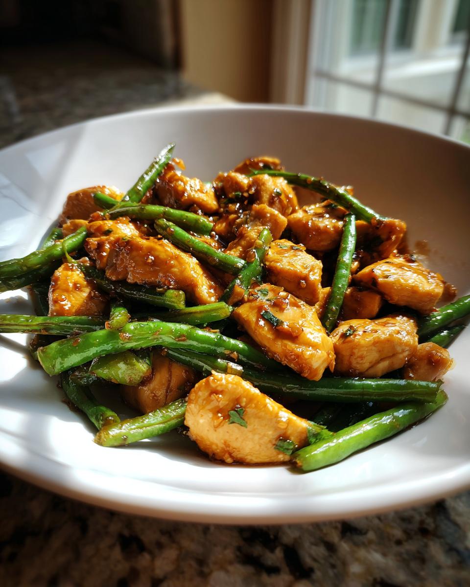 Close-up of glazed chicken pieces mixed with bright green beans, representing the amazing chicken and green beans recipe.