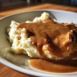 Close-up of creamy mashed potatoes generously covered with rich homemade brown gravy.