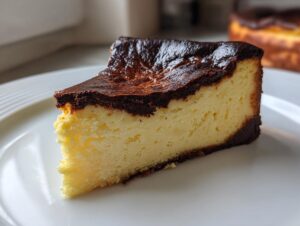 A close-up slice of creamy Basque burnt cheesecake showing the signature dark, caramelized top and pale yellow interior.