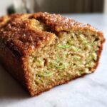 A close-up cross-section view of moist snickerdoodle zucchini bread showing visible shreds of green zucchini throughout the crumb.