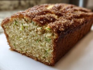 A close-up view of a freshly baked snickerdoodle zucchini bread loaf with a sugary, cinnamon topping.