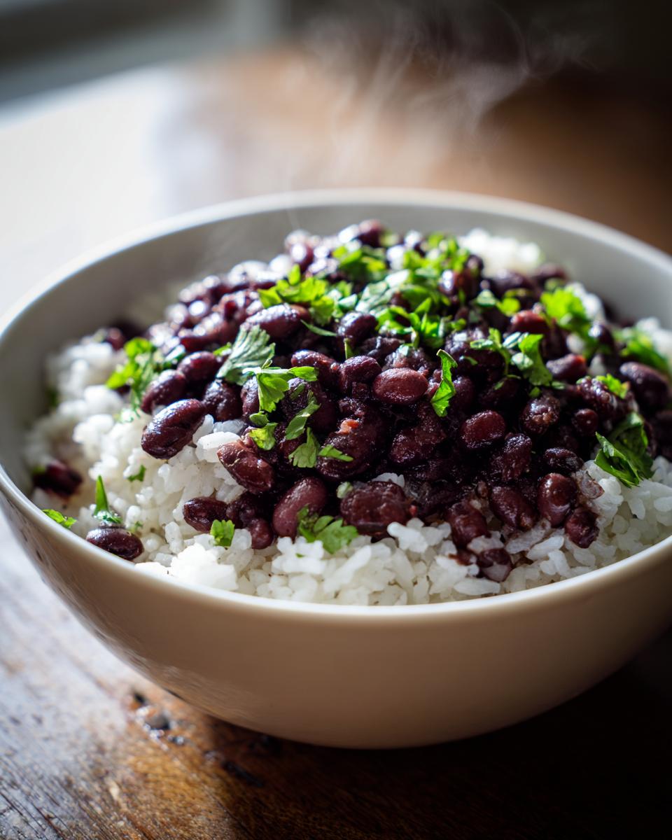 Close-up of a steaming bowl of white rice topped with dark red beans and fresh chopped cilantro, representing delicious beans and rice.