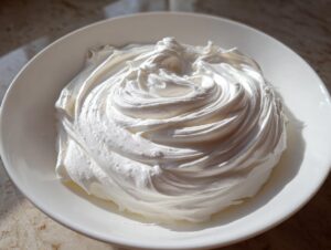 A bowl of thick, bright white, freshly mixed sugar cookie icing that hardens, swirled beautifully.