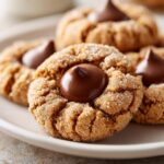 Close-up of a perfectly baked peanut butter blossom cookie rolled in sugar with a chocolate kiss center.
