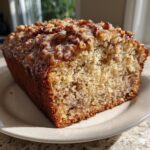 Close-up of a slice of sweet alabama pecan bread showing a moist crumb and pecan glaze topping.