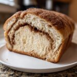 Close-up of a loaf of amazing cinnamon swirl bread, showing a thick interior swirl and sugary top crust.