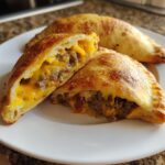 Close-up of a bacon cheeseburger pocket cut in half showing ground beef, bacon, and melted cheddar cheese filling.