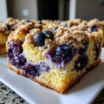 Close-up of a moist slice of Blueberry French Toast Casserole topped with fresh blueberries and brown sugar streusel.