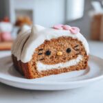 A cross-section of a cinnamon roll cake sanrio designed to look like Hello Kitty's face with cream cheese filling.