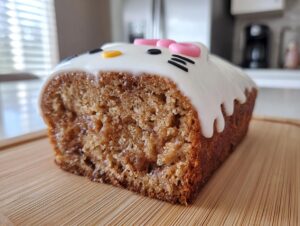 Close-up of a slice of cinnamon roll cake sanrio loaf with white icing decorated like Hello Kitty.