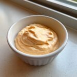 A close-up of creamy, orange-tinted big mac sauce served in a small white ramekin dish.