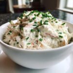 A white bowl filled with creamy cold crab dip, generously topped with chopped green chives.