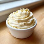 A swirl of creamy, pale yellow roasted garlic aioli recipe served in a small white ramekin.