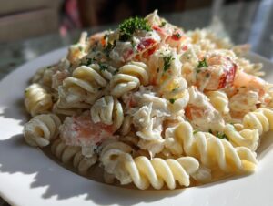 Close-up of a creamy seafood salad recipe with crab, shrimp, and fusilli pasta, garnished with parsley.
