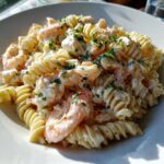 Close-up of creamy seafood salad recipe with crab, shrimp, and fusilli pasta, garnished with parsley.