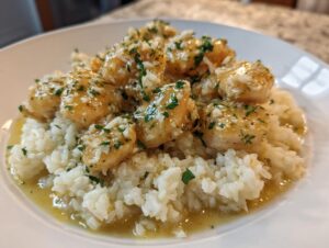 Close-up of easy chicken scampi served over creamy garlic parmesan rice, topped with herbs.