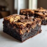 A close-up of a fudgy, square brookies bar showing the brownie base and cookie topping with melted chocolate chips.