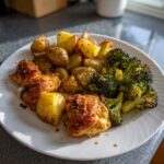 A plate featuring garlic parmesan chicken and potatoes alongside roasted broccoli florets.