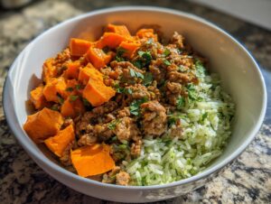 A close-up of a ground turkey sweet potato taco bowl featuring seasoned ground turkey, bright orange sweet potato chunks, and cilantro-lime rice.
