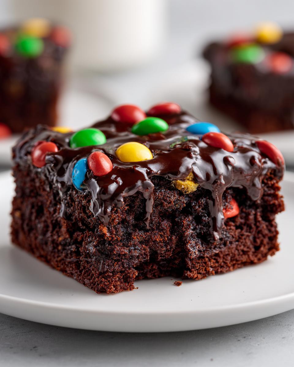A rich, fudgy square of homemade cosmic brownies topped with thick chocolate glaze and colorful candy-coated chocolates.