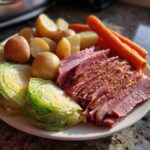 A plate featuring sliced instant pot corned beef and cabbage, potatoes, and carrots ready to eat.