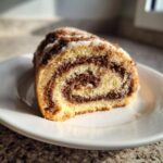 Close-up of a slice of Italian nut roll cookies showing the swirled filling and white glaze.