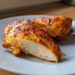 Close-up of a perfectly cooked, juicy boneless skinless chicken thighs, cut to show the moist white interior and seasoned crust.