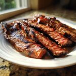 Close-up of perfectly grilled and sliced skirt steak, showing a medium-rare interior and a shiny glaze.