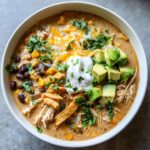 Overhead view of Martina McBride's Creamy Chicken Tortilla Soup topped with avocado, sour cream, and cheese.