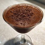 Close-up of a rich, frothy non alcoholic chocolate martini garnished with dark chocolate shavings.