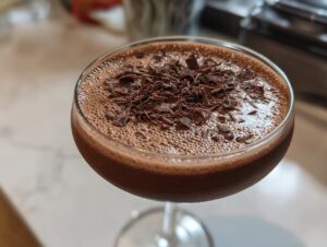 Close-up of a rich, frothy non alcoholic chocolate martini garnished with dark chocolate shavings.