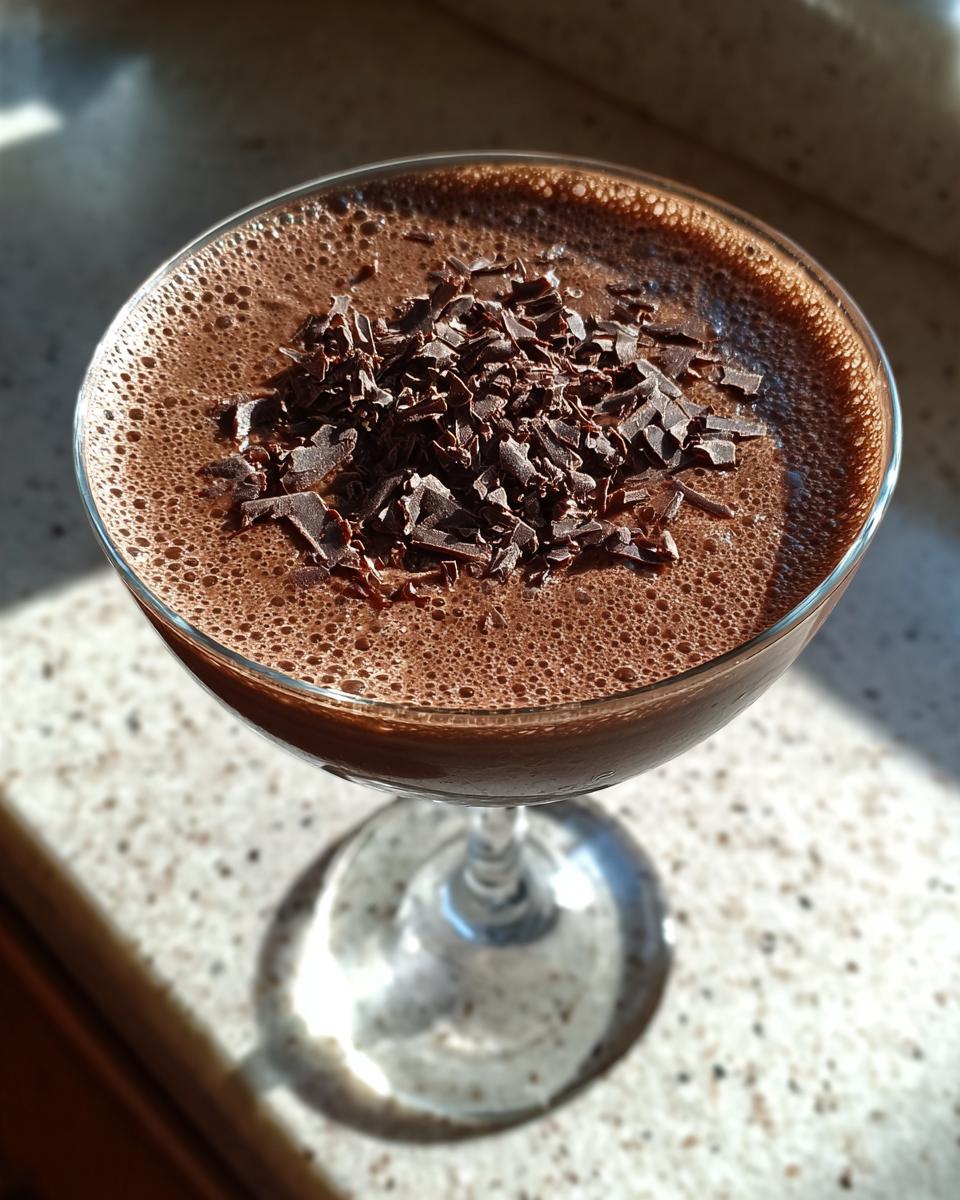 Close-up of a frothy non alcoholic chocolate martini garnished with dark chocolate shavings in a coupe glass.