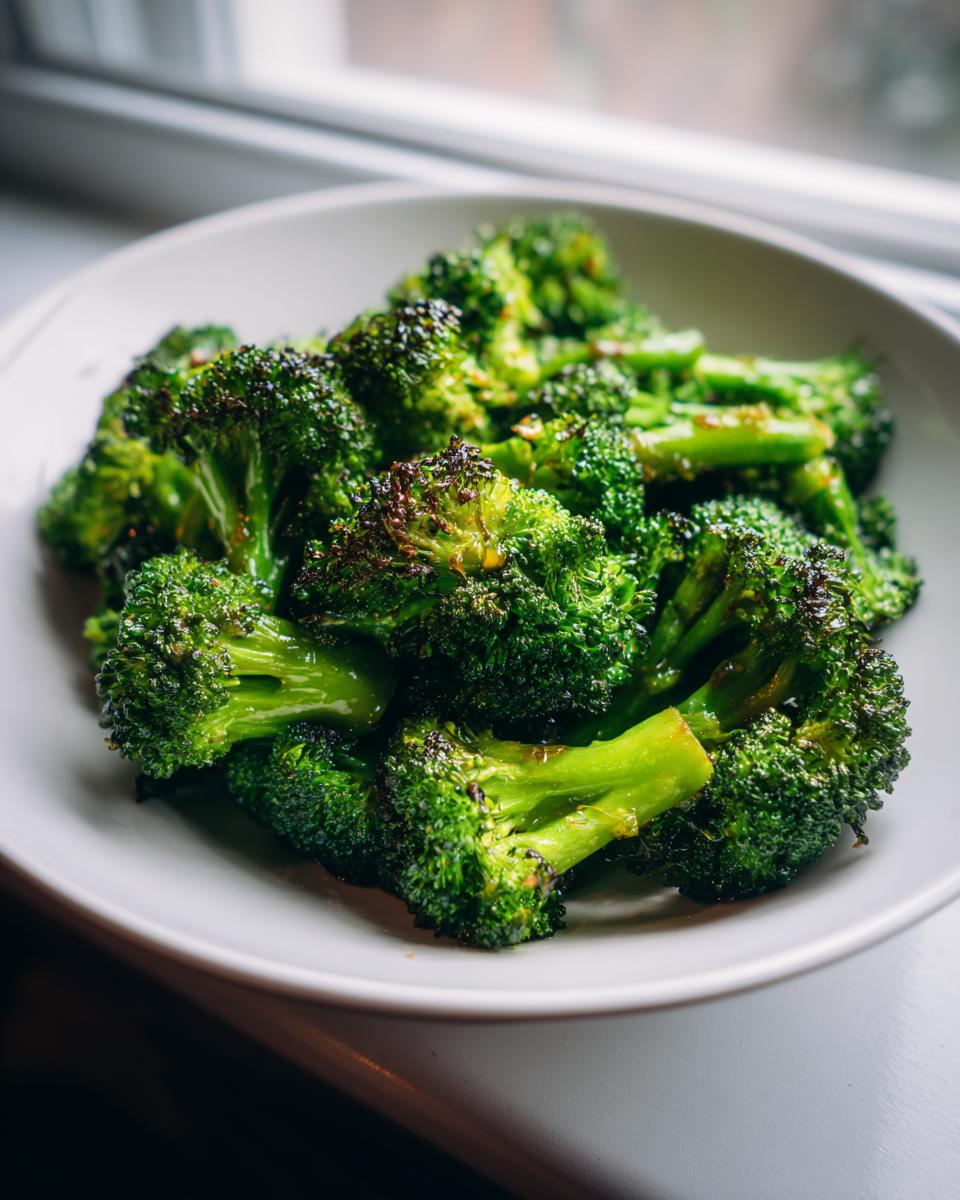 A bowl of perfectly roasted broccoli florets coated in a shiny roasted broccoli vinegar mustard glaze.