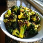 Close-up of perfectly roasted broccoli florets coated in a shiny roasted broccoli vinegar mustard glaze served in a white bowl.