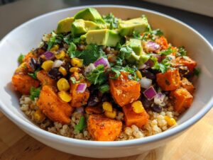 Close-up of a vibrant roasted sweet potato taco bowl featuring quinoa, black beans, corn, red onion, and topped with fresh avocado.