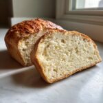 Close-up of a loaf of homemade beer bread, sliced to show the soft, airy interior crumb.