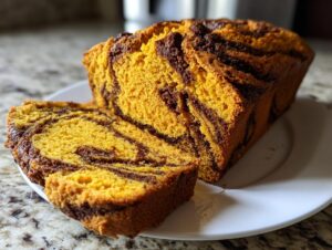 A loaf of vibrant orange sourdough pumpkin cinnamon swirl bread with a slice cut, showing the dark cinnamon swirl pattern.