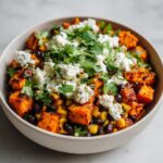Close-up of sweet potato taco bowls cottage cheese, black beans, corn, and fresh cilantro.