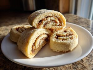 Four slices of tasteful bites Italian nut roll cookies stacked on a white plate, showing the swirl filling.