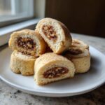 Close-up of several tasteful bites italian nut roll cookies, showing the spiced nut filling inside the rolled dough.