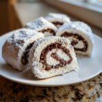 Close-up of several slices of Valerie Bertinelli Italian Nut Roll Cookies dusted heavily with powdered sugar.