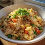 Close-up of a bowl of freshly made chicken fried rice topped with chopped green onions.