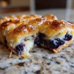 Close-up of a blueberry cream cheese croissant bake cut open, showing melted cream cheese and juicy blueberries.