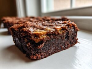 A close-up of a rich, fudgy square of brown butter ooey gooey bars showing a shiny, crackly top.
