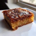 A close-up of a single square of brown butter ooey gooey bars with a thick, glossy, caramelized topping.