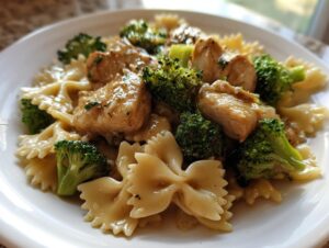 A close-up of cowboy butter lemon bowtie chicken with broccoli served on a white plate.