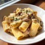 Close-up of creamy garlic butter chicken rigatoni pasta coated in a rich sauce and garnished with parsley.