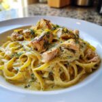 Close-up of creamy salmon pasta featuring fettuccine noodles, chunks of cooked salmon, fresh dill, and lemon zest.