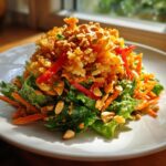 A vibrant plate of crispy rice salad with peanut sesame dressing, topped with crunchy fried rice and peanuts.